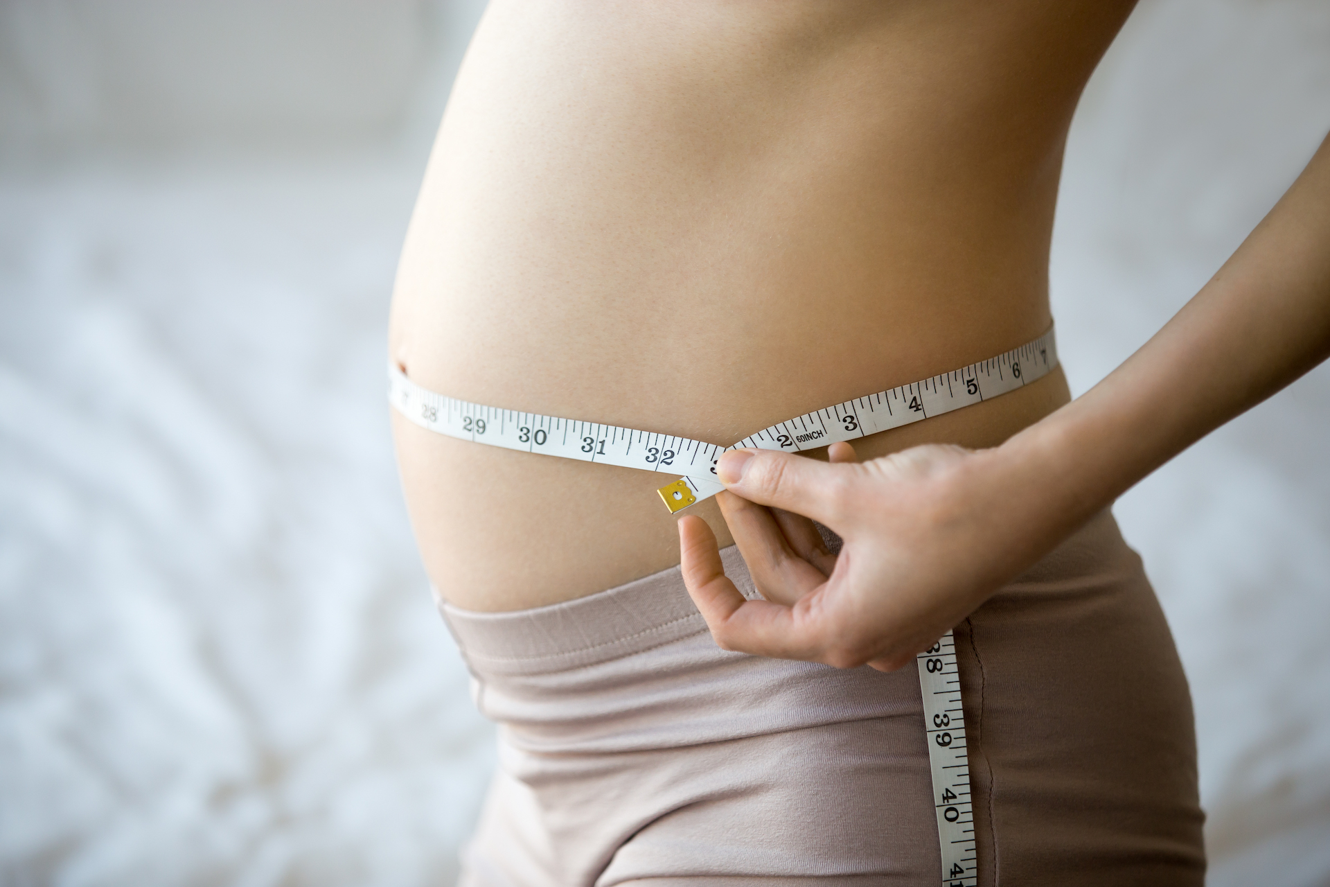 pregnant woman measuring her waist